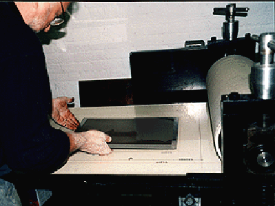 PLACING THE PLATE ON THE PRESS - All photogravures are hand printed, using mechanized or manual Brand presses. The plate is laid in place on the press in a premarked position to insure proper alignment.